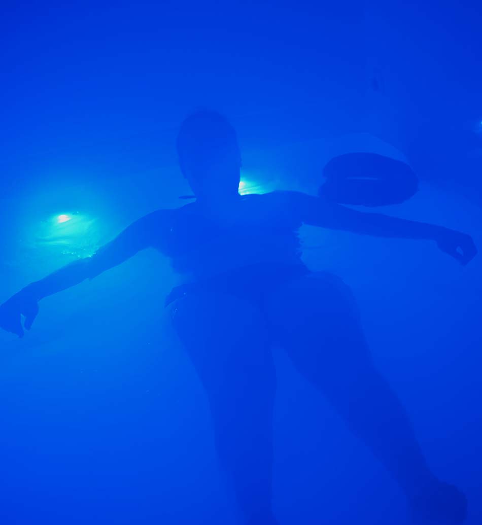 Silhouette of a woman in a floatation bath, blue atmosphere.